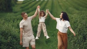 Joyful family moment in a green field during summer, capturing love and playfulness.